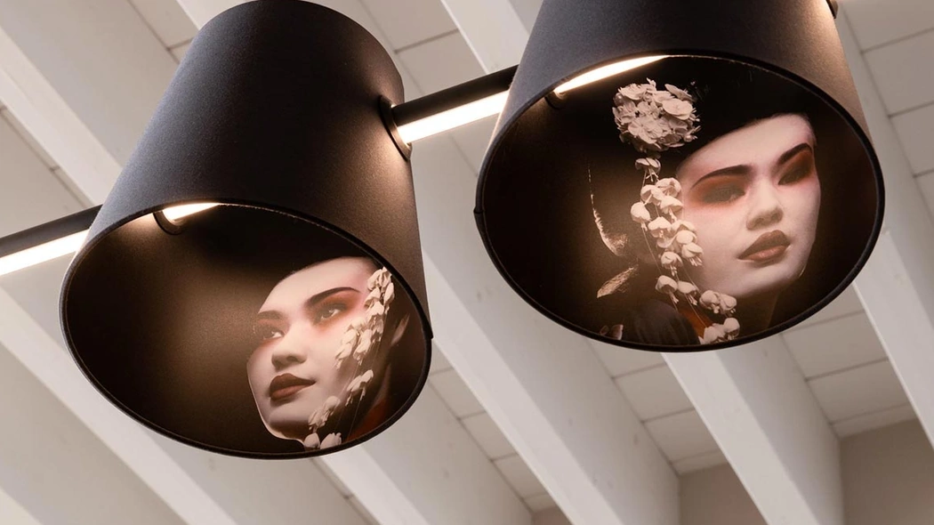 Lampada a sospensione costituita da una lunga e minimale barra di luce a led che trafigge un paralume in tessuto Cupido di Karman